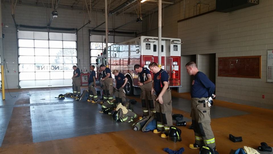 Firefighters Standing in a Formation Putting on Their Gear in a Fire House